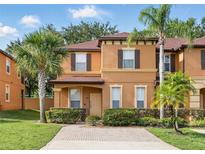 Inviting two-story townhome with neutral stucco exterior, manicured landscaping, and brick-paved driveway at 203 La Mirage St, Davenport, FL 33897