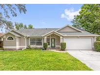 Charming single-story home featuring a well-manicured lawn, attached two car garage, and a decorative front door at 248 Country Landing Blvd, Apopka, FL 32703