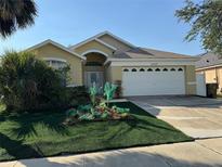 Inviting single-story home with a well-maintained front yard, manicured bushes, and an attached two car garage at 2567 Oneida Loop, Kissimmee, FL 34747
