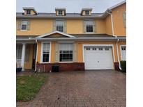 Charming yellow townhome featuring a brick paved driveway and single-car garage, adding curb appeal at 4981 Alita Ter, St Cloud, FL 34769