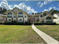 Inviting two-story condo with large windows, landscaped lawn, and charming walkway under a sunny blue sky at 5017 Laguna Bay Cir # 96, Kissimmee, FL 34746