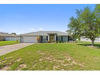 Charming single-story home featuring a well-manicured lawn, attached garage and inviting yellow front door at 6006 Country Walk Ln, Winter Haven, FL 33880