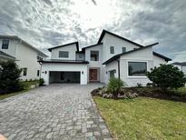 Stunning modern home with a brick driveway, attached garage and beautifully landscaped front yard at 9004 Santorini Dr, Orlando, FL 32827