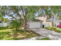 Charming home featuring a two-car garage, well-manicured lawn, and mature landscaping at 14006 Yellow Wood Cir, Orlando, FL 32828