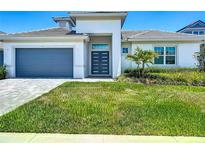 Contemporary home featuring a well-manicured lawn, gray garage door, and a modern entrance with sleek, dark gray doors at 235 Hampton Loop, Davenport, FL 33837