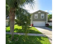 Charming two-story home featuring a two-car garage and a well-manicured lawn with mature palm trees at 3303 Amberley Park Cir, Kissimmee, FL 34743