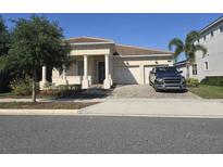 Beautiful single-story home with a columned porch, brick driveway, and two-car garage at 8270 Topsail Pl, Winter Garden, FL 34787
