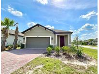Charming single-story home with well-manicured lawn, brick driveway, and attached two-car garage at 1001 Umbria Dr, Poinciana, FL 34759