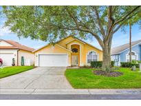 Charming single-Gathering home featuring an attached two-car garage and a well-manicured front lawn with mature tree at 1113 Casterton Cir, Davenport, FL 33897