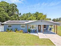 Charming blue home with a carport, well-maintained lawn, and solar panels in a sunny setting at 1408 Polk City Rd, Haines City, FL 33844