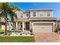 Beautiful two-story home with a stone accent, a lush lawn, and a brick driveway for added curb appeal at 152 Whirlaway Dr, Davenport, FL 33837