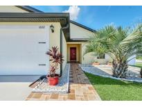 Inviting single-Gathering home features a two-car garage and a red brick walkway leading up to the red front door at 1602 Steely Dr, Dundee, FL 33838