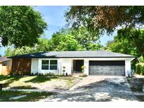 Charming single-story home with a brick accent, dark garage door, and lush landscaping at 2074 Dunsford Dr, Orlando, FL 32808