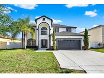 Stunning two-story home featuring a black-trimmed, white exterior, lush lawn, and ample driveway space at 242 Anson Dr, Kissimmee, FL 34758