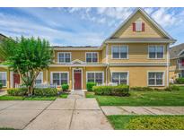 Charming two-story townhome with red door, white picket fence, and lush landscaping at 2614 Lodi Cir # 106, Kissimmee, FL 34746