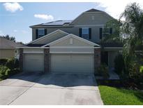 Two-story home with a three-car garage, solar panels, and well-maintained landscaping at 3003 Cobham Rd, Kissimmee, FL 34758
