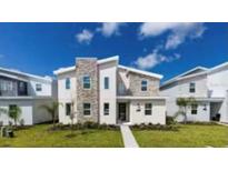 Modern two-story home featuring stone accents, a manicured lawn, and a bright, inviting entrance at 9118 Sommerset Hills Dr, Davenport, FL 33896