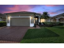 Charming single-story home with brick driveway, lush lawn, and attached two-car garage at 124 Ashton Dr, Davenport, FL 33837