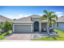 Charming single-story home with a well-maintained front yard, palm tree, and a colorful turquoise front door at 140 Trinity Ridge Cir, Davenport, FL 33897