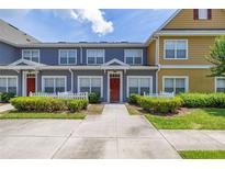 Charming townhome exterior featuring colorful facades, white picket fences, and landscaped greenery under a sunny sky at 2620 Lodi Cir # 103, Kissimmee, FL 34746