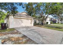 Beige single-Gathering home with two-car garage and large tree in the front yard, complemented by an expansive driveway at 3370 Cypress Point Cir, St Cloud, FL 34772