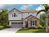 Charming two-story home featuring a stone facade, gray siding, well-manicured lawn, and an attached two-car garage at 3781 Deer Ridge Dr, Mount Dora, FL 32757