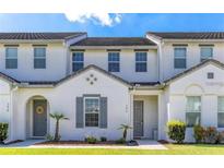 Charming townhome featuring a modern white exterior, landscaped lawn, and stylish gray door at 386 Captiva Dr, Davenport, FL 33896