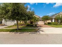 Charming single-story home with a well-manicured lawn and a brick-paved driveway and mature landscaping at 5009 E Fountainwood Dr, St Cloud, FL 34772