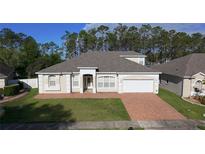 Inviting single-story home with a manicured lawn, brick driveway, and attached two-car garage at 518 Brighton Dr, Davenport, FL 33897