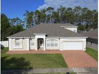 Charming single-story home with a well-manicured lawn and a brick-paved driveway leading to an attached garage at 518 Brighton Dr, Davenport, FL 33897