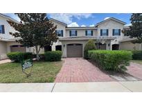 Inviting townhouse with a brick-paved driveway, beautiful landscaping, and an attached one-car garage at 13885 Arclid St, Orlando, FL 32832