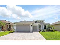 Beautiful single-story home featuring a three-car garage, well-maintained landscaping, and a brick driveway at 142 Olympus Way, Kissimmee, FL 34759
