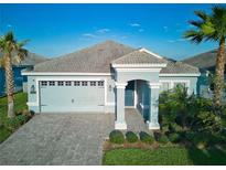 Charming single-story home featuring a paver driveway, a two-car garage, and lush tropical landscaping under a bright blue sky at 1508 Bunker Drive Bunker, Davenport, FL 33896
