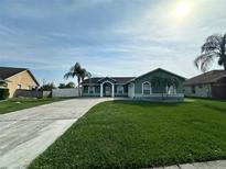 Charming single-story home with lush green lawn, palm trees, and a long concrete driveway at 2410 Sweetwater Blvd, St Cloud, FL 34772
