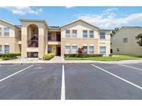Inviting condo with beige exterior, second-floor entrance, neat landscaping, and convenient parking at 2826 Club Cortile Cir # B, Kissimmee, FL 34746