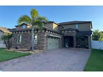 Beautiful two-story home with stone accents, a brick driveway, and lush tropical landscaping at 3159 Somerset Park Dr, Orlando, FL 32824