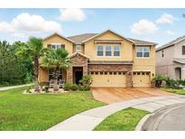 Charming tan two-story home featuring a brick-paved driveway, manicured lawn, and a spacious three-car garage at 3899 Mount Vernon Way, Kissimmee, FL 34741