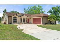 Charming single-story home featuring a well-manicured lawn and a red two-car garage at 621 Rebecca Dr, St Cloud, FL 34769