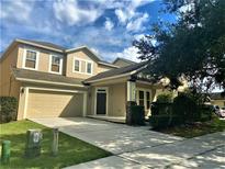Two-story home with a two-car garage, covered porch, well-maintained lawn, and mature tree offering shade at 6957 Northwich Dr, Windermere, FL 34786