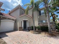 Charming two-story home with a tile roof, two-car garage, and lush tropical landscaping at 833 Brunello Dr, Davenport, FL 33897