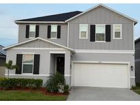 Charming two-story home featuring gray siding, black shutters, and a well-manicured front yard at 895 Overpool Ave, Davenport, FL 33896