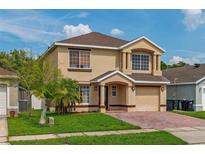 Charming two-story home with a well-manicured lawn, brick driveway, and inviting entrance at 1425 Carey Glen Cir, Orlando, FL 32824