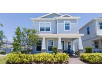Charming two-story home with a covered front porch, manicured landscaping, and a welcoming entrance at 14309 Lanikai Beach Dr, Orlando, FL 32827