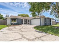 Charming single-story home with a cracked circular driveway, lush lawn, and a two-car garage at 1436 Nolton Way, Orlando, FL 32822