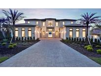 Elegant home with meticulously landscaped front yard, long paved driveway, and prominent palm trees, radiating luxury at 15121 Pendio Dr, Montverde, FL 34756