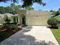 Charming home featuring a brick driveway, attached garage, and manicured landscaping at 2312 Twickingham Ct, Clermont, FL 34711