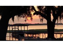 Picturesque waterfront view from the dock with a covered area, complemented by a vibrant sunset at 2740 Barker Rd, St Cloud, FL 34771