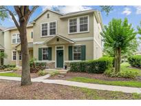 Charming two-story townhome featuring a well-maintained lawn and inviting green door at 7144 Five Oaks Dr, Harmony, FL 34773
