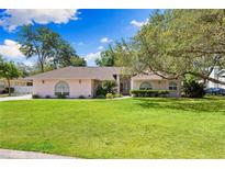 Charming single story home featuring a lush lawn, mature trees, and a beautiful front facade with arched windows at 7222 Stanford Dr, Lakeland, FL 33809