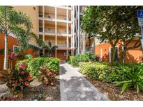 Apartment building featuring multiple stories with balconies, lush landscaping, and a brick walkway at 9055 Treasure Trove Ln # 409, Kissimmee, FL 34747